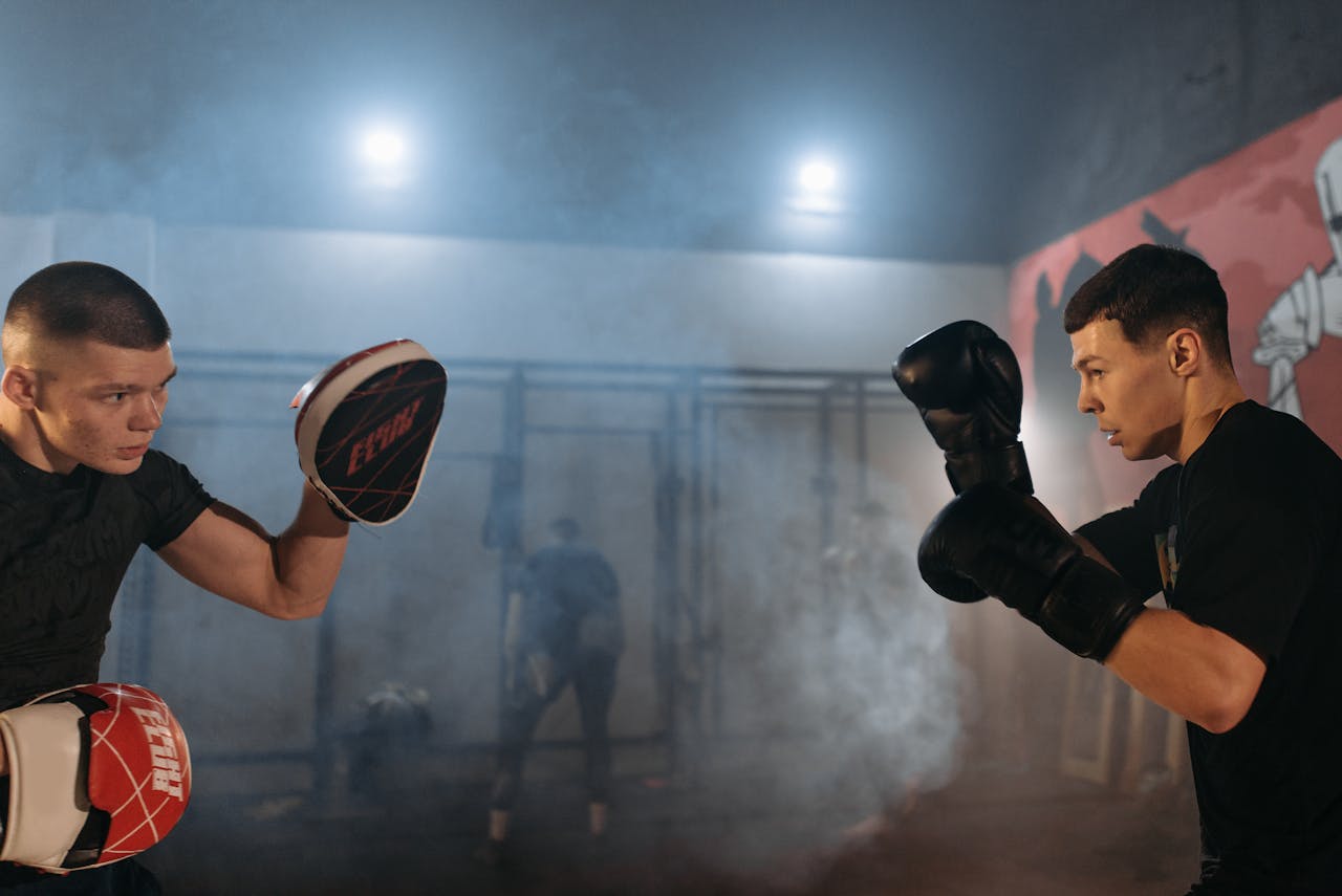 Boxers sparring in a dimly lit gym, showcasing skill and determination.